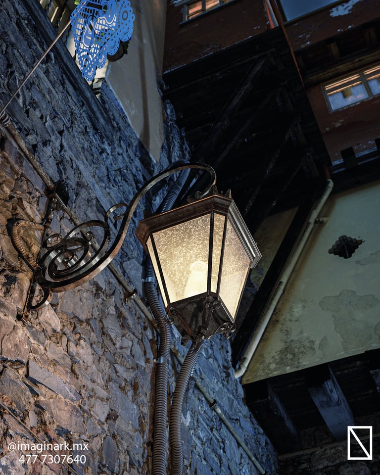 Farola iluminada montada en pared de piedra de edificio antiguo al atardecer
