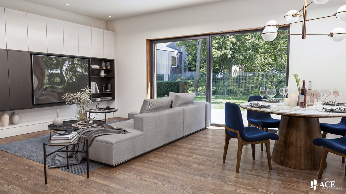 Modern open-plan living room with gray sectional sofa, wooden dining table with blue chairs, and floor-to-ceiling windows overlooking greenery.